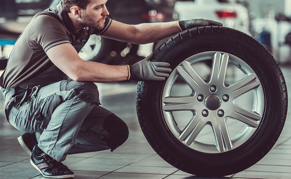 Mechanic holding a tyre - MOT, Servicing & Tyres Swanage